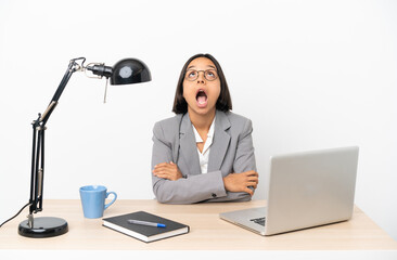 Young business mixed race woman working at office looking up while smiling