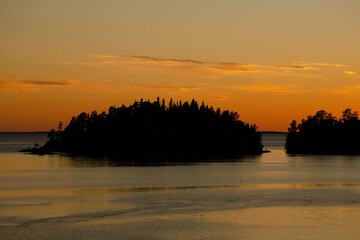 Sunset sky over the lake and black silhouettes of the islands. Beautiful photo of nature