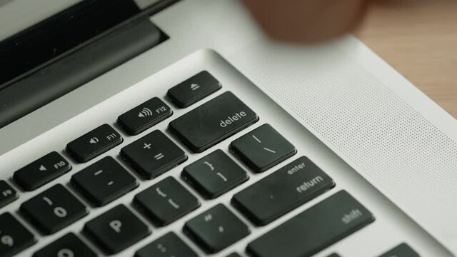 CRASH ZOOM IN Caucasian male furiously pushing delete button on a laptop keyboard, angry man trying to delete something