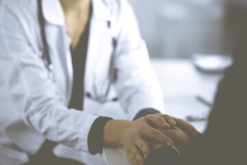 Obraz premium Unknown woman-doctor is reassuring her female patient, close-up. Physician is consulting and giving some advices to a woman. Concepts of medical ethics and trust. Empathy in medicine