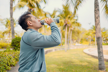 Fototapeta na wymiar Young sport man drink water after jogging, running in the park. Sport thirsty and resting after exercise.