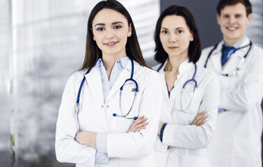 Group of young professional doctors is standing as a team with arms crossed in a hospital office and is ready to help patients. Medical help, insurance in health care, best disease treatment and