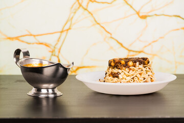 Famous traditional Arabic, Egyptian dish - Koshari. National Kushari in a white plate on dark wooden background with tomato sauce