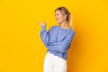 Young Russian woman isolated on yellow background pointing to the side to present a product