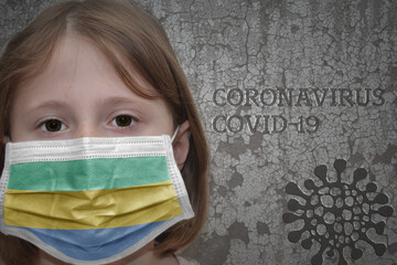 Little girl in medical mask with flag of gabon stands near the old vintage wall with text coronavirus, covid, and virus picture.