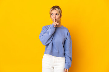 Young Russian woman isolated on yellow background showing a sign of silence gesture putting finger in mouth