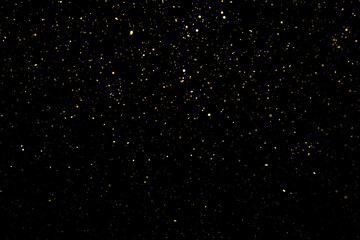 Shiny golden particles on black background