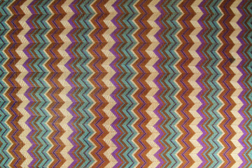 The pattern on the knitted fabric is a herringbone made of multi-colored stripes. Abstract background