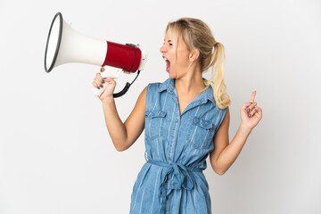 Young Russian woman isolated on white background shouting through a megaphone to announce something in lateral position