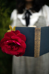 Young college student holding a poetry book and a rose. Concept of romance - 418687774