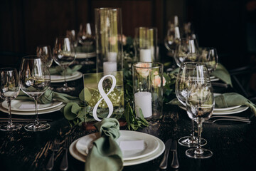 Wedding banquet. The festive table is served with plates with napkins and name cards, glasses and cutlery, and decorated with flower arrangements and candles