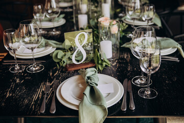 Wedding banquet. The festive table is served with plates with napkins and name cards, glasses and cutlery, and decorated with flower arrangements and candles