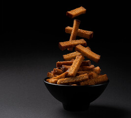 Falling rye bread croutons on black background