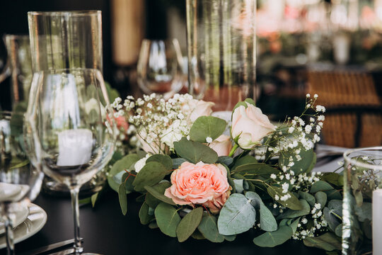 Wedding banquet. The festive table is served with plates with napkins and name cards, glasses and cutlery, and decorated with flower arrangements and candles