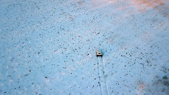 View from above. Inspector raid on a winter reserve in Russia on a swamp vehicle. A jeep on large wheels drives through a snow-covered field.