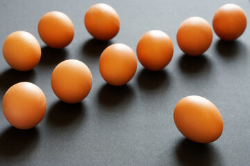 Ten upscale golden chicken eggs lie on a gray, rough rustic table. Selective focus