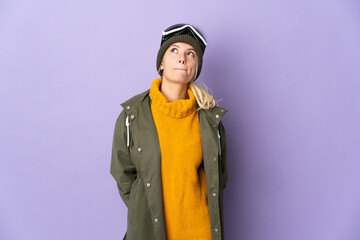 Skier Russian girl with snowboarding glasses isolated on purple background and looking up