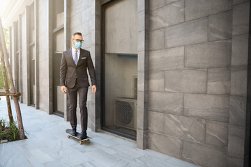 Businessman wear face mask and walking or transport by skateboard to office