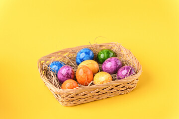 Colorful easter eggs in the basket on the yellow background.