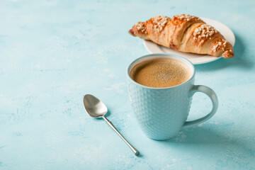 Cup of coffee and fresh croissant on a plate