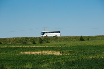 White bus driving on a countryside road in summer
