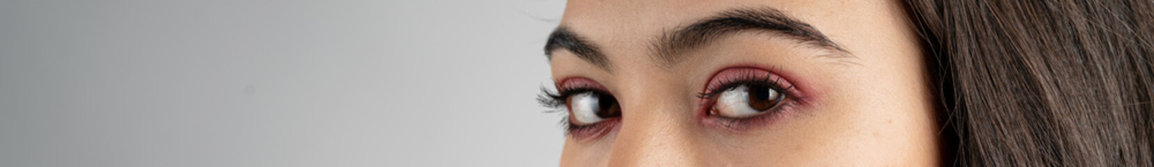 Fototapeta na wymiar Macro shot of woman eye makeup with red eyeshadow. Close-up of woman eyelashes. Panoramic shot.