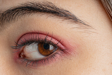 Fototapeta premium Macro shot of woman eye makeup with red eyeshadow. Close-up of woman eyelashes. Square shot.