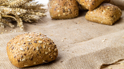 Baguette bread. Rye bakery with crusty loaves and crumbs. Fresh loaf of rustic traditional bread with wheat grain ear or spike plant on natural cotton background. Concept - Cooking at Home.