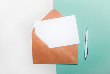 On a light and light green background, an open craft envelope and a blank sheet of paper with space to insert text or illustrations. Template. Copy space