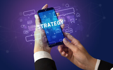 Obraz premium Female hand typing on smartphone with STRATEGY inscription, social media concept