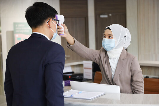 Receptionist ้check Body Or Face Temperature Of Guests Before Entry To Hotel, Covid-19 Pandemic And New Normal Protection 