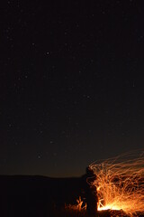 Person next to campfire in wind storm