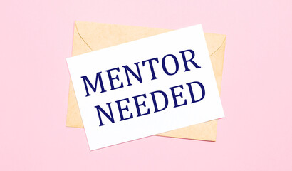 On a light pink background - a craft envelope. It has a white sheet of paper that says MENTOR NEEDED.
