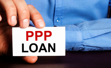 PPP LOAN is written on a white business card in a man's hand. Advertising concept