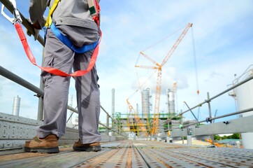 Foreman, supervisor, engineer standing on scaffolding and put on safety harness during working at...