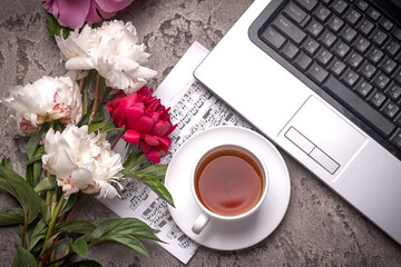 Coffe, peonies and laptop on grey vintage background