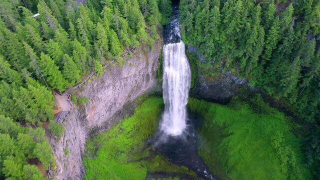 Aerial tilt down shot of beautiful waterfall from cliff in forest, drone flying forward over cascade - Salt Creek Falls, Oregon