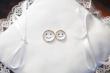 Wedding rings on white pad with drawn faces