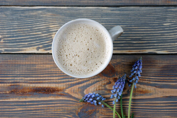 Blue muscari flowers and a cup of coffee on a wooden background