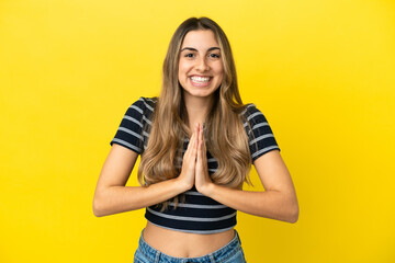 Young caucasian woman isolated on yellow background keeps palm together. Person asks for something