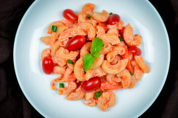Top view macaroni pasta with tomato sauce, pork and vegetables.
