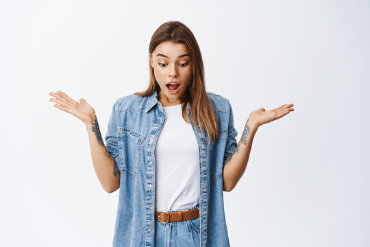 Surprised Blond Girl Gasping In Disbelief, Raising Hands Sideways And Looking Down With Shocked Face, Say Wow, Impressed By Bottom Advertisement, White Background