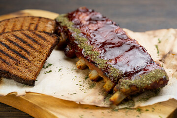 grilled pork ribs with barbecue sauce and grilled bread slices. pork with tomato spice sauce on a wooden board