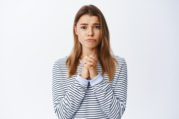 Sad woman pleading and asking for help, begging you, asking please and frowning upset, standing...