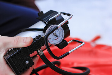 Man pumping air into tire of tube with mechanical pump on winter day. Equipment, device.