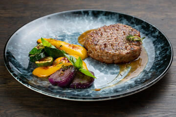 grilled minced beef cutlet with grilled vegetables and barbecue sauce. fried zucchini, onion and pepper with minced pork cutlet