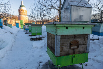 hives in winter on the territory of the monastery. multi-colored hives in the snow. Colored bee...
