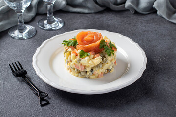 Traditional Russian salad Olivier with salted salmon on a dark background. Festive presentation.