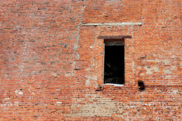 A hole where a door should have been in the old brick wall of a crumbling industrial building.