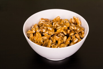 Walnuts, a bunch of peeled walnuts in white bowl on black table
